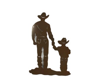 May include: Metal silhouette of two cowboys, one tall and one short, walking side-by-side. Both are wearing cowboy hats and boots. The silhouette is brown and is cut out against a white background.