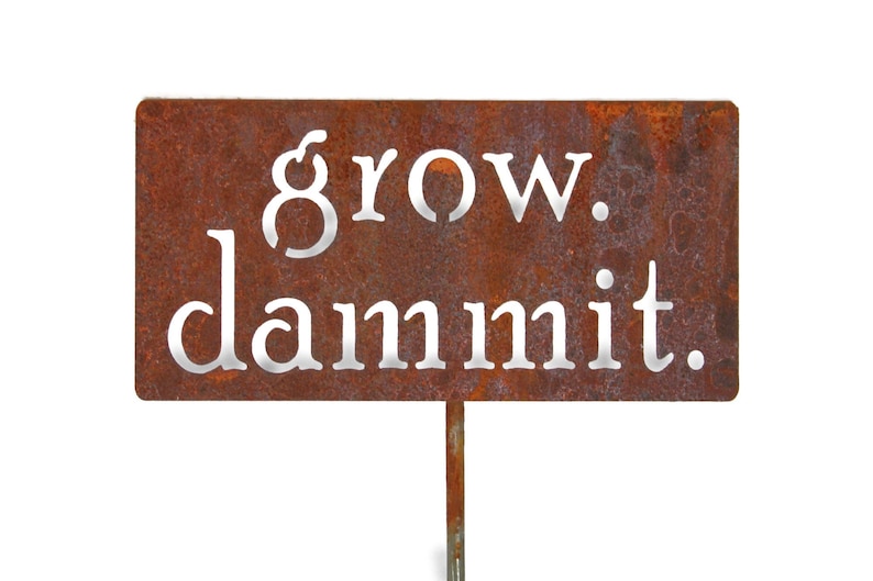 May include: Rusty metal garden stake with the words "grow. dammit." in white lettering.