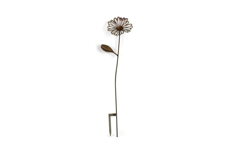 May include: A metal daisy garden stake with a brown center and white petals. The stem and leaf are dark brown. The stake has a two-pronged base for easy placement in the garden. A decorative outdoor accent.