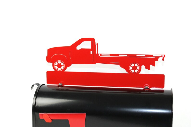 Pode incluir: Tope de caixa de correio de metal vermelho em forma de caminh&atilde;o de plataforma. O caminh&atilde;o est&aacute; em estilo silhueta e tem uma base vermelha.