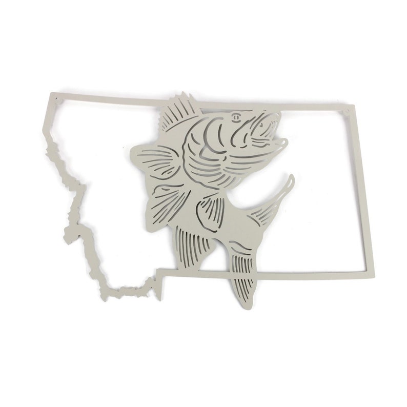 May include: A metal wall art piece featuring a silhouette of the state of Montana with a stylised fish jumping out of the outline. The piece is painted in a light grey colour.