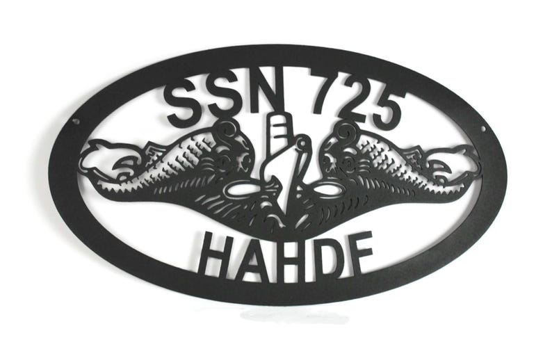 Puede incluir: Un letrero de pared ovalado de metal negro con un dise&ntilde;o recortado de la insignia de guerra submarina de la Marina de los EE. UU., tambi&eacute;n conocida como delfines. El texto SSN 725 est&aacute; arriba y el texto HAHDF est&aacute; abajo del &oacute;valo.
