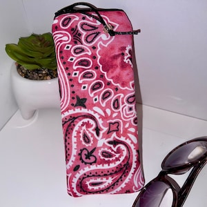 May include: A pink and black bandana print zippered pouch for sunglasses or other small items.