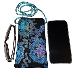 May include: A black fabric phone case with a blue and purple floral pattern, a teal rope strap, and a decorative tassel. A pair of brown-framed sunglasses and a smartphone are next to the case.