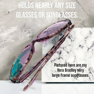 Pode incluir: Um par de &oacute;culos de sol grandes, com padr&atilde;o de tartaruga, com lentes roxas. Os &oacute;culos de sol est&atilde;o apoiados numa superf&iacute;cie de m&aacute;rmore branco. O texto "HOLDS NEARLY ANY SIZE GLASSES OR SUNGLASSES." est&aacute; no topo da imagem. O texto "Pictured here are my Vera Bradley very large frame sunglasses." est&aacute; na parte inferior da imagem.