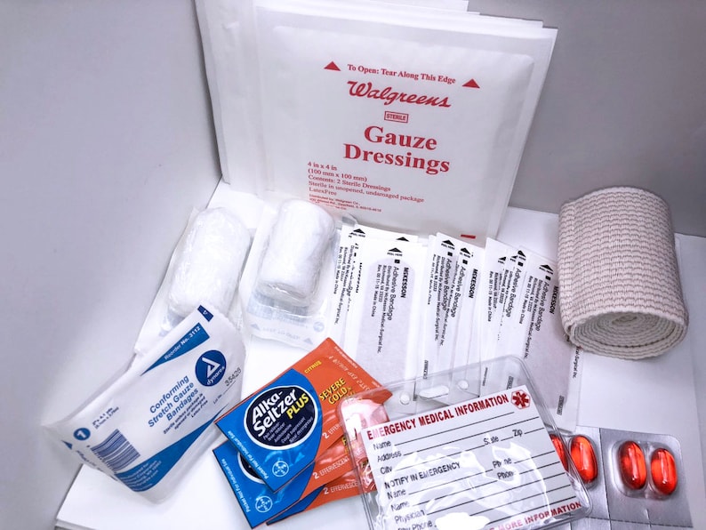 May include: A first aid kit with various supplies, including gauze dressings, bandages, a roll of gauze, pain relief tablets, and an emergency medical information card. The kit is labeled "Walgreens" and includes the text "Gauze Dressings".