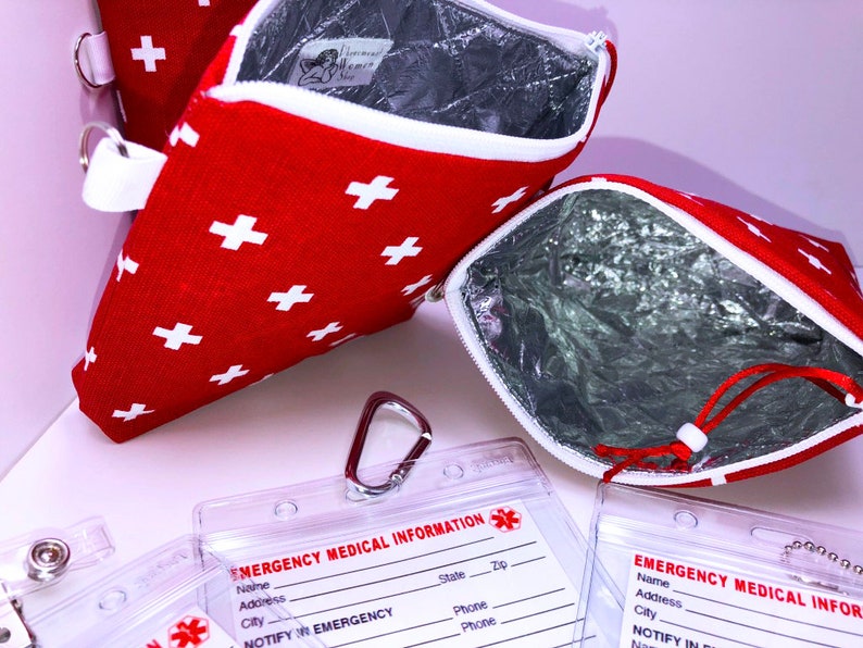 May include: Two red zippered pouches with white crosses and a silver lining. The pouches are open to show the silver lining. There are three clear plastic card holders with the text "EMERGENCY MEDICAL INFORMATION" and a red cross symbol. The card holders have spaces for name, address, city, state, zip, phone, and notify in emergency.