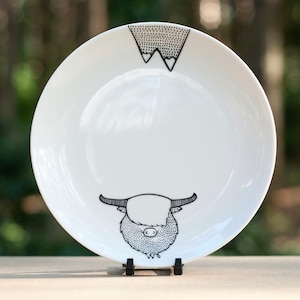 Può includere: Piatto in ceramica bianca con un'illustrazione in bianco e nero di una mucca delle Highlands e una catena montuosa. La mucca è rivolta verso lo spettatore e la catena montuosa è capovolta.