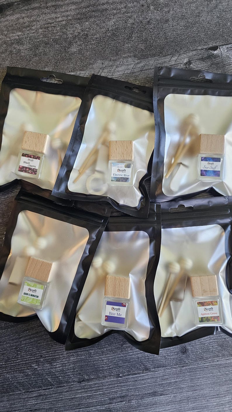 Puede incluir: Varias botellas de vidrio peque&ntilde;as con tapas de madera, cada una etiquetada con un nombre de aroma diferente, est&aacute;n empaquetadas en bolsas de pl&aacute;stico transparente con bordes negros. Los aromas incluyen "Blueberry", "Electric Blue", "Star Stuff", "Odor Eliminator", "Bite Me" y "Apricot Grove".