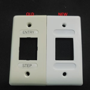 以下が含まれることがあります： 2つの長方形の壁プレートの比較。左側のプレートはオフホワイトで「OLD」と表示され、「ENTRY」と「STEP」の文字が書かれています。右側のプレートは白で「NEW」と表示されています。どちらのプレートにも正方形の開口部と2つのネジ穴があります。