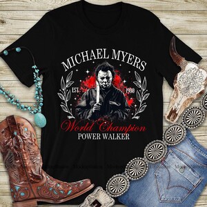 May include: Black t-shirt with a graphic of Michael Myers holding a knife, the text reads "MICHAEL MYERS" above and "World Champion POWER WALKER" below. The design includes a red splatter effect and the year "1980".