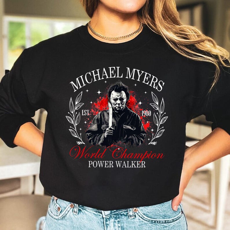 May include: Black sweatshirt with a graphic of Michael Myers holding a knife. The text "MICHAEL MYERS" is above the image, and "World Champion POWER WALKER" is below. The design includes the year "1980" and a decorative wreath.