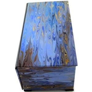 Puede incluir: Una caja de madera de color azul y marr&oacute;n con vetas de m&aacute;rmol y una tapa con bisagras. La caja tiene un patr&oacute;n de m&aacute;rmol decorativo en la parte superior e inferior.