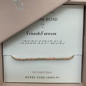 May include: A gold-filled Morse code bracelet with pink and gold beads, presented in a pink box. The card reads "Friends Forever" with the Morse code translation. The jewelry is from Willow Road, CA.