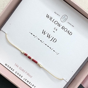 May include: A 14k gold filled Morse code bracelet featuring small red and gold beads on a thin gold chain. The bracelet is displayed on a white card printed with the text Willow Road CA, WWJD, and Morse code symbols in a pink box.