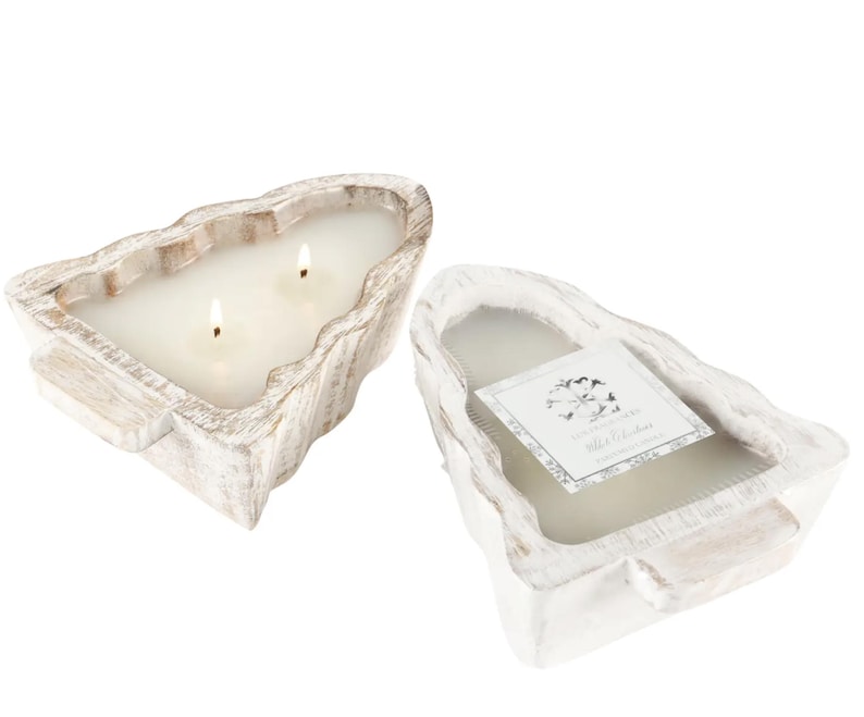 May include: Two-wick candle in a distressed, white-washed wooden container. The candle has a rectangular shape with a natural, organic edge. A label is visible on the second candle, with text and a floral design. The candle is a home decor item.
