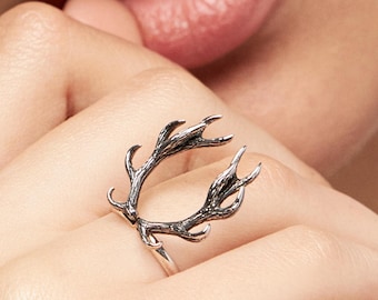 Puede incluir: Un anillo de plata con un diseño de asta de ciervo detallado. El anillo se lleva en el dedo de una persona.