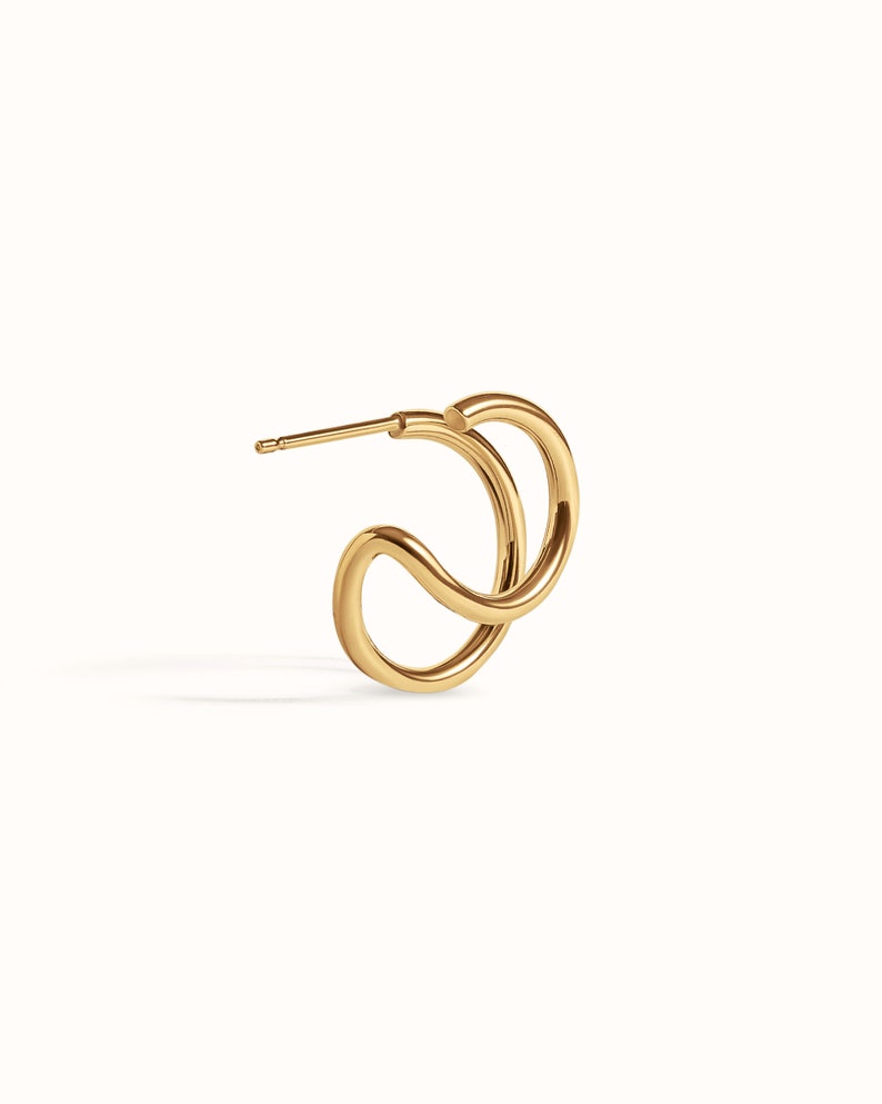 Puede incluir: Pendientes de aro dobles de color dorado con un dise&ntilde;o retorcido. Los pendientes est&aacute;n hechos de un metal liso y brillante.
