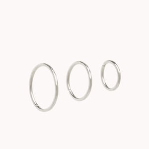 May include: Three silver hoop earrings of different sizes. The earrings are smooth and have a polished finish.
