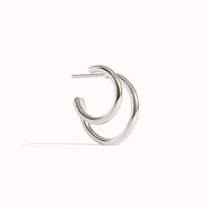 Puede incluir: Pendientes de aro dobles de plata. Los aros est&aacute;n conectados entre s&iacute; y tienen un dise&ntilde;o simple y minimalista.