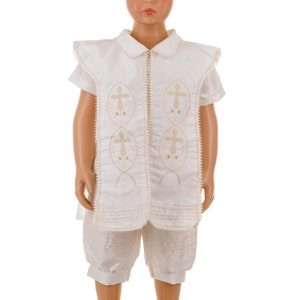 May include: White christening outfit with gold embroidered crosses on the front. The outfit includes a short-sleeved shirt and shorts.