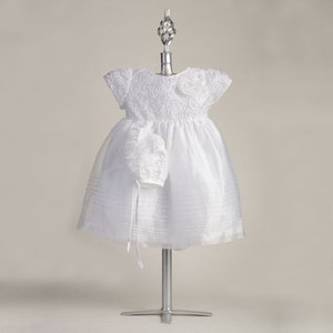Pu&ograve; includere: Abito bianco per neonata con corpetto in pizzo e gonna in tulle. L'abito &egrave; abbinato a un berretto.