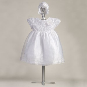 Pu&ograve; includere: Abito bianco per neonata con corpetto in pizzo e gonna in tulle. L'abito &egrave; abbinato a un cappello bianco.