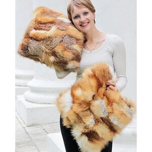 May include: Two fox fur throw pillows in a variety of shades of brown, orange, and white. The pillows are being held by a person.