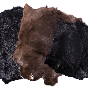 Könnte beinhalten: Drei Stücke Pelz in verschiedenen Brauntönen und Schwarz. Das Fell ist weich und flauschig und so angeordnet, dass seine Textur zur Geltung kommt.