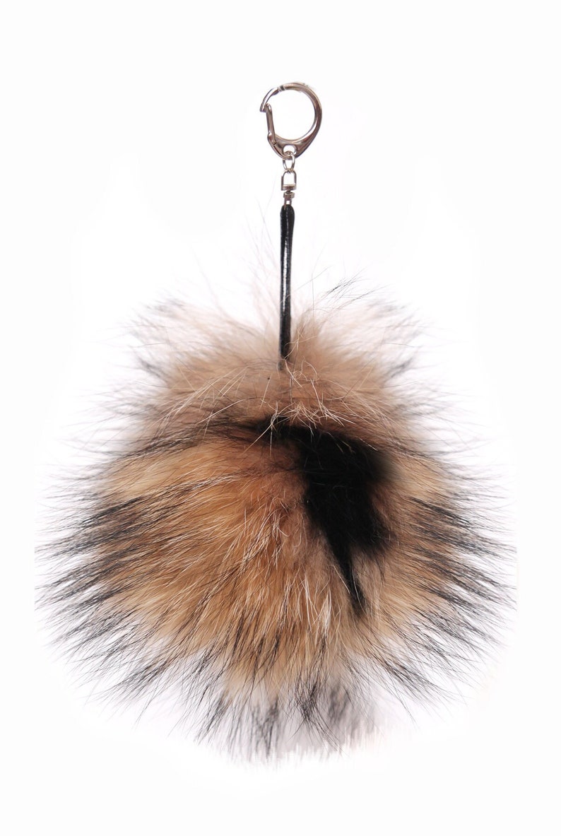 May include: A brown and black fur pom-pom keychain with a silver key ring.