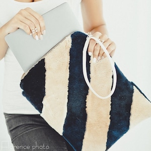 May include: A black and white striped faux fur tote bag with a white handle. The bag is made of a soft, plush material and has a casual, trendy style.