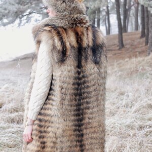 May include: A long, brown and black fur vest with a hood. The vest is made of a soft, luxurious fur and has a sleek, stylish design.