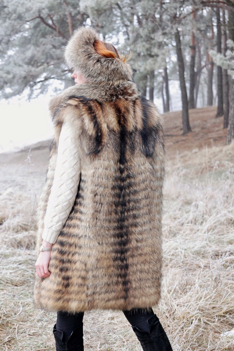 May include: A long, brown and black fur vest with a hood. The vest is made of a soft, luxurious fur and has a sleek, stylish design.