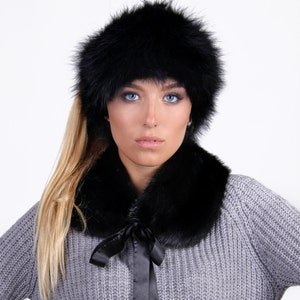 Puede incluir: Un gorro de piel negro y un cuello de piel a juego. El gorro se lleva en la cabeza de una persona con el pelo largo y rubio. El cuello se lleva alrededor del cuello de una persona que lleva un su&eacute;ter gris.