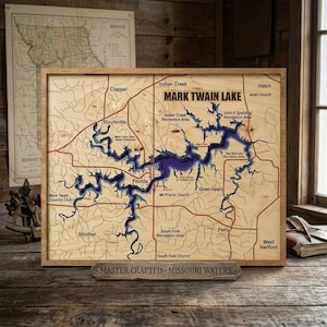 May include: A rectangular wooden wall map of Mark Twain Lake featuring a light wood grain finish with a deep purple recessed lake bed. The map includes black text labels for locations like Stoutsville, Florida, and Perry, with a base plaque reading MASTER CRAFTED - MISSOURI WATERS.