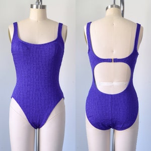 Puede incluir: Un traje de baño de una pieza morado con un patrón geométrico y un escote en la espalda.