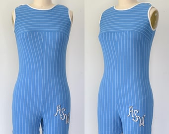 Puede incluir: Un romper sin mangas de color azul claro con finas rayas verticales blancas, un borde de cuello redondo blanco y las letras ASW bordadas en blanco en la pierna izquierda. La prenda se muestra en un maniquí desde el frente y de lado.