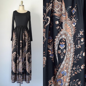 May include: A long black maxi dress with a paisley print in shades of brown, blue, and white. The dress has a fitted bodice and a flowing skirt.