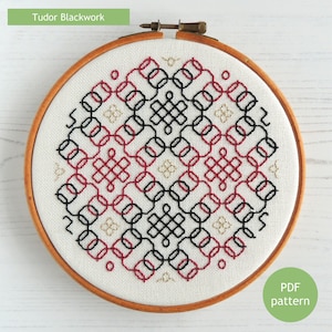 Può includere: Un primo piano di un cerchio da ricamo finito con un disegno geometrico di punto nero in filo rosso, nero e oro. Il cerchio è in legno e ha uno sfondo in tessuto bianco. Il disegno si chiama "Tudor Blackwork" ed è un modello PDF.
