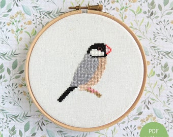 以下が含まれることがあります： 木製の刺繍枠に入ったジャワ雀のクロスステッチ刺繍。鳥はグレー、黒、タン色のクロスステッチで、赤い嘴と黒い頭が特徴です。「Java Sparrow」の文字が上に、「PDF pattern」の文字が下にあります。