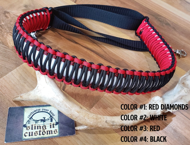 May include: Red, white, and black paracord sling with a diamond pattern. The sling is made by Sling It Customs and is customizable. The text "customize your hunt" and "sling it customs" is on a white card.
