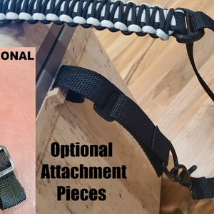May include: A black and white braided strap with a black strap and a metal hook. The strap is attached to a black strap with a metal buckle. The text "OPTIONAL" is visible in the image. The text "Optional Attachment Pieces" is also visible in the image.