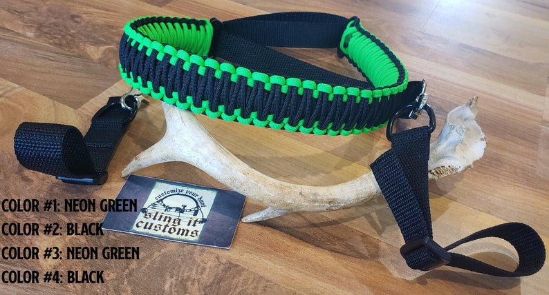 May include: A black and neon green paracord sling with two black straps. The sling is made with a braided paracord design. The text "sling it customs" is visible on a white card.