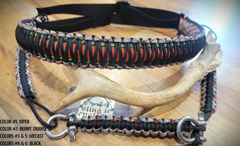 May include: A black and orange paracord dog collar and lead. The collar and lead are made of woven nylon cord and feature metal hardware. The image also includes a deer antler.