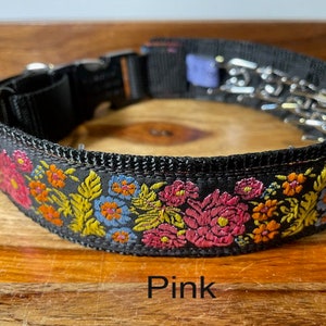 May include: A black nylon collar featuring a vibrant embroidered floral pattern in shades of pink, orange, yellow, and blue. The collar includes a black plastic side-release buckle, a metal D-ring, and a metal prong chain attachment. The text Pink is visible.