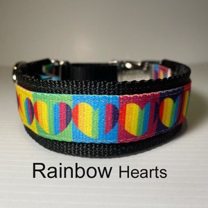May include: A black dog collar with a rainbow heart pattern. The collar has a silver buckle and is adjustable. The text "Rainbow Hearts" is printed below the collar.