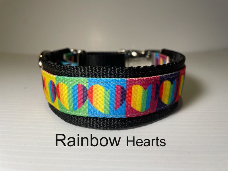 May include: A black dog collar with a rainbow heart pattern. The collar has a silver buckle and is adjustable. The text "Rainbow Hearts" is printed below the collar.