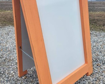 May include: A wooden A-frame sign with a white chalkboard insert. The sign is painted a bright orange color and has a chain attached to the top.