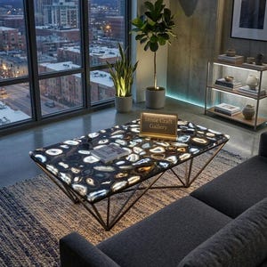 May include: A modern coffee table with a black and white stone top and a geometric metal base. The table is in a living room setting with a city view. The text on the table reads "Stone Craft Gallery".