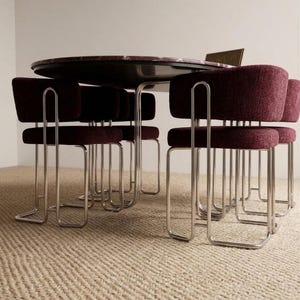 May include: A round dining table with a dark marble top is surrounded by six burgundy upholstered chairs with chrome frames. The chairs have a unique, curved design. The table and chairs are set on a beige woven rug.